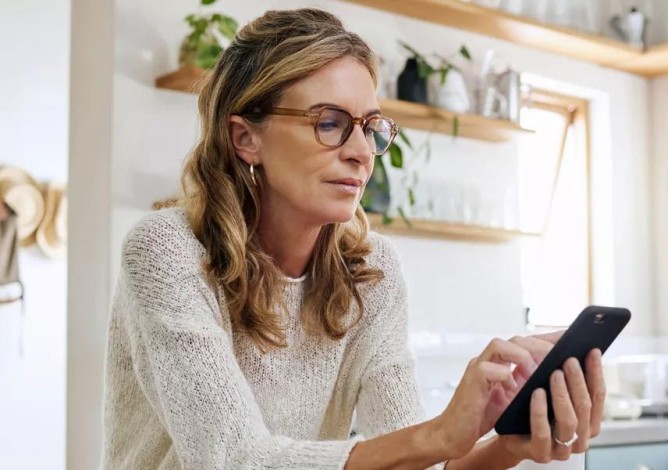 A woman looking discovering the similarities and differences of an IRA and 401(k) on her phone.